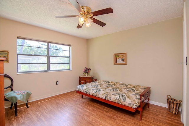 bedroom featuring ceiling fan, light hardwood / wood-style flooring, and a textured ceiling