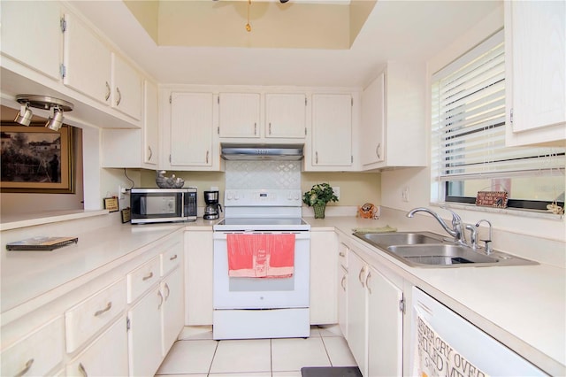 kitchen with white appliances, a raised ceiling, sink, light tile patterned floors, and white cabinetry