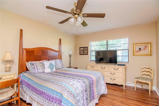 bedroom featuring a textured ceiling, ceiling fan, and light wood-type flooring