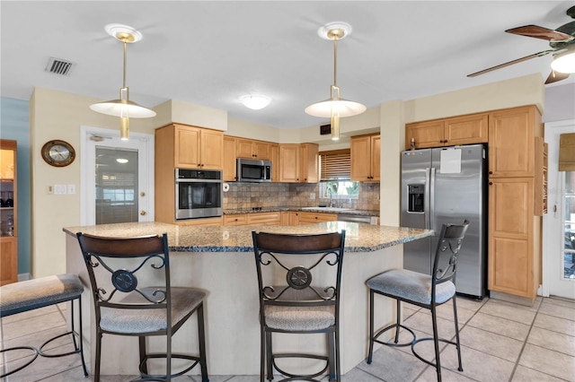 kitchen with a kitchen island, tasteful backsplash, appliances with stainless steel finishes, sink, and light tile patterned flooring