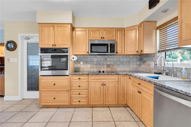 kitchen featuring sink, stainless steel appliances, decorative backsplash, and light tile patterned floors