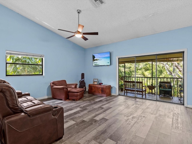 living room featuring ceiling fan, vaulted ceiling, a textured ceiling, and hardwood / wood-style flooring