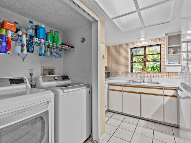 washroom featuring light tile patterned floors, sink, washing machine and dryer, and a textured ceiling