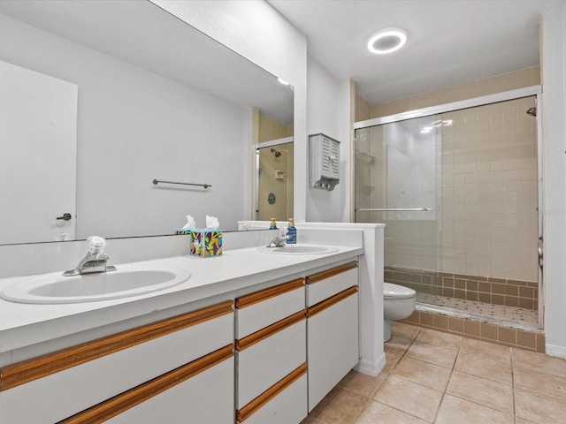 bathroom featuring tile patterned flooring, a shower with shower door, vanity, and toilet