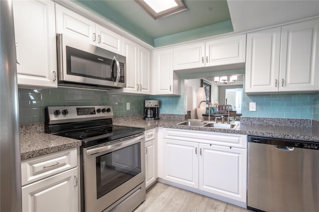 kitchen with light hardwood / wood-style flooring, backsplash, white cabinets, appliances with stainless steel finishes, and sink