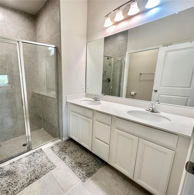 bathroom with tile patterned floors, a shower with door, and vanity