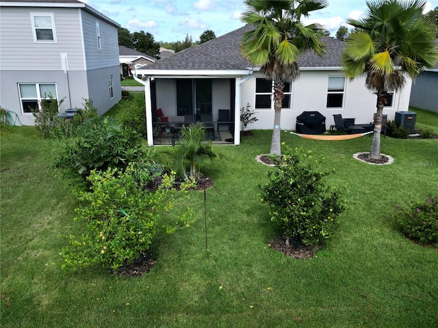 back of house featuring central air condition unit, a sunroom, and a lawn