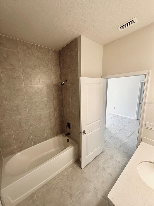 bathroom with vanity, a textured ceiling, tile patterned floors, and tiled shower / bath