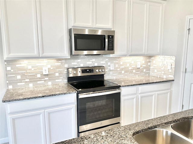 kitchen featuring white cabinets, dark stone countertops, backsplash, and appliances with stainless steel finishes