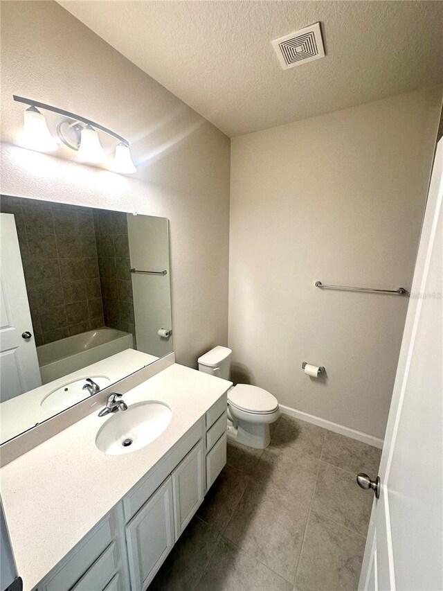 bathroom featuring vanity, a bathtub, tile patterned floors, toilet, and a textured ceiling