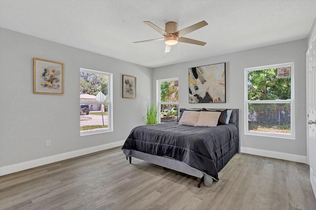 bedroom featuring ceiling fan, light hardwood / wood-style floors, and a textured ceiling