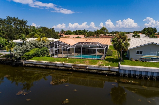 back of house with a lawn, a water view, a lanai, and an outdoor pool