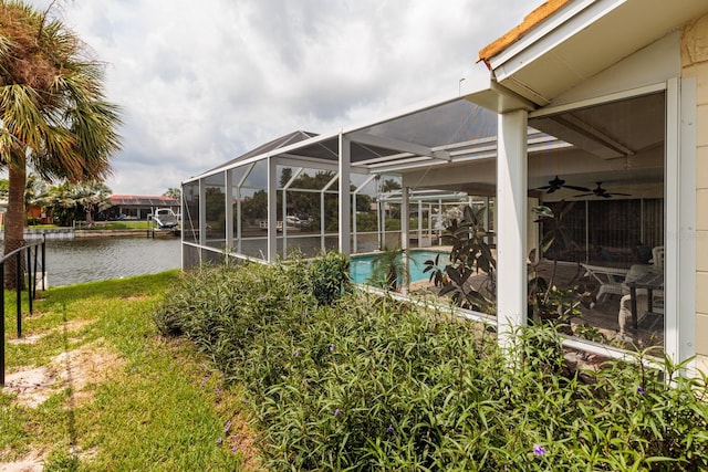 view of yard with a water view, ceiling fan, and a lanai