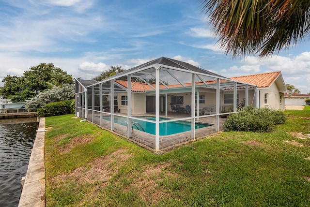 back of house with a water view, a patio area, a lanai, and a lawn