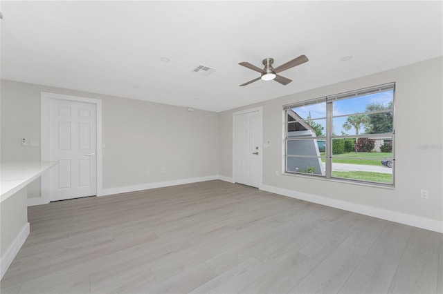 empty room featuring baseboards, visible vents, and light wood finished floors