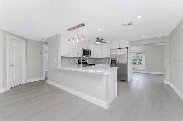 kitchen with visible vents, stainless steel appliances, a peninsula, white cabinets, and light countertops