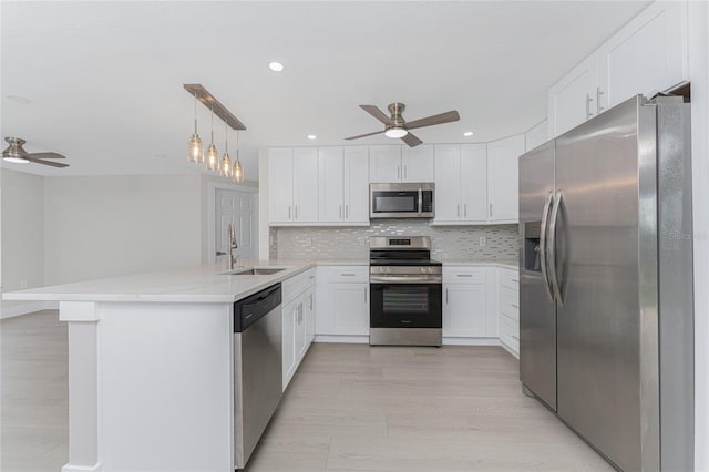 kitchen with a sink, tasteful backsplash, stainless steel appliances, a peninsula, and ceiling fan