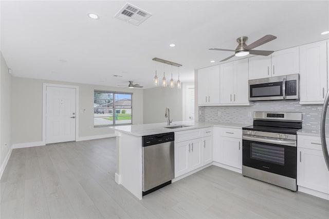 kitchen with visible vents, backsplash, a peninsula, stainless steel appliances, and a sink