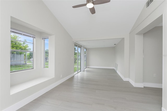 interior space featuring visible vents, light wood-type flooring, baseboards, and vaulted ceiling