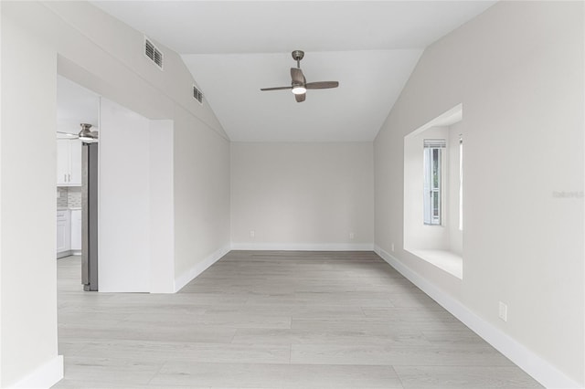 empty room featuring ceiling fan, visible vents, light wood-style flooring, and vaulted ceiling