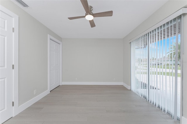 spare room featuring light wood-type flooring, visible vents, baseboards, and a ceiling fan