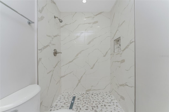 bathroom featuring a marble finish shower and toilet