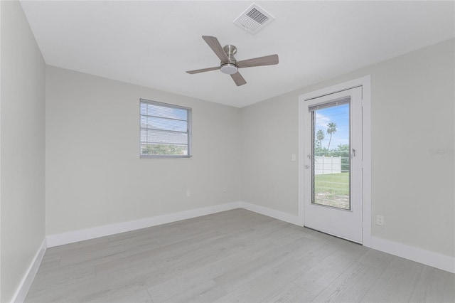 empty room with light wood finished floors, visible vents, plenty of natural light, and baseboards