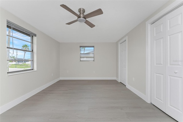 unfurnished bedroom featuring light wood-style floors, baseboards, and ceiling fan