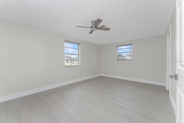 spare room with baseboards, light wood-style floors, a healthy amount of sunlight, and ceiling fan