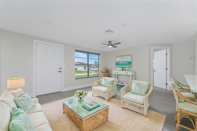 living room featuring visible vents, ceiling fan, baseboards, and wood finished floors