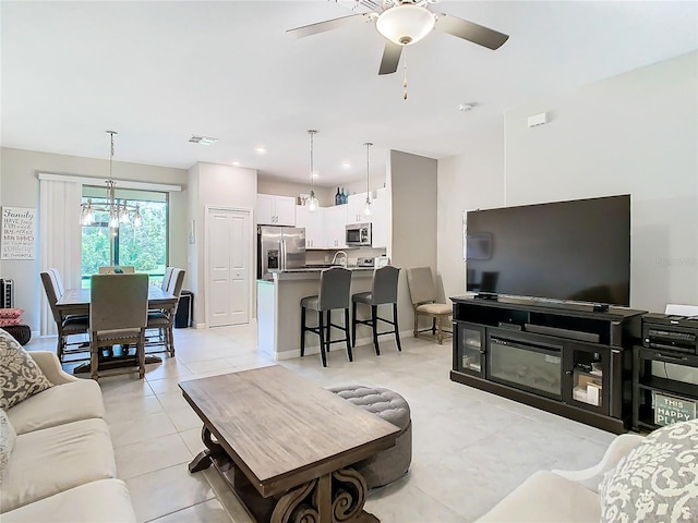 tiled living room with ceiling fan with notable chandelier