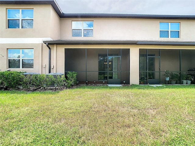 back of property with a sunroom and a lawn