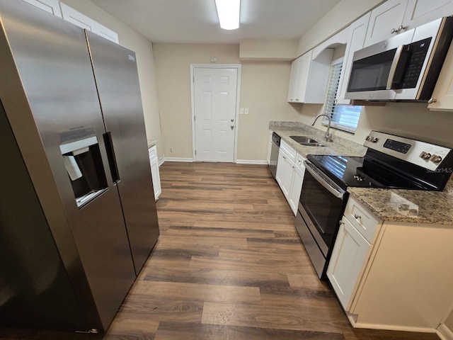 kitchen with sink, dark wood-type flooring, light stone countertops, stainless steel appliances, and white cabinets