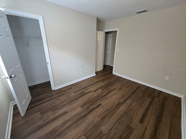 unfurnished bedroom with dark wood-type flooring and a closet