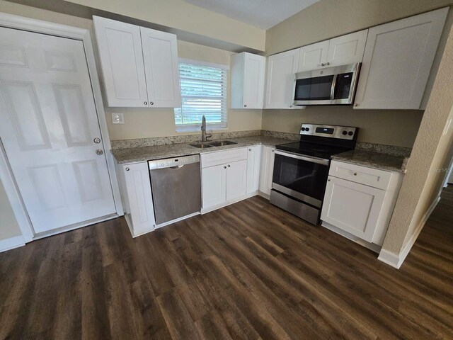 kitchen featuring dark wood-type flooring, white cabinetry, light stone counters, sink, and stainless steel appliances