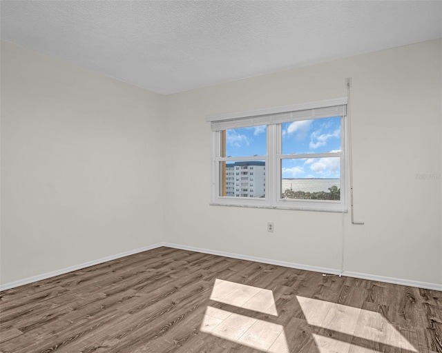 spare room with a textured ceiling and hardwood / wood-style flooring