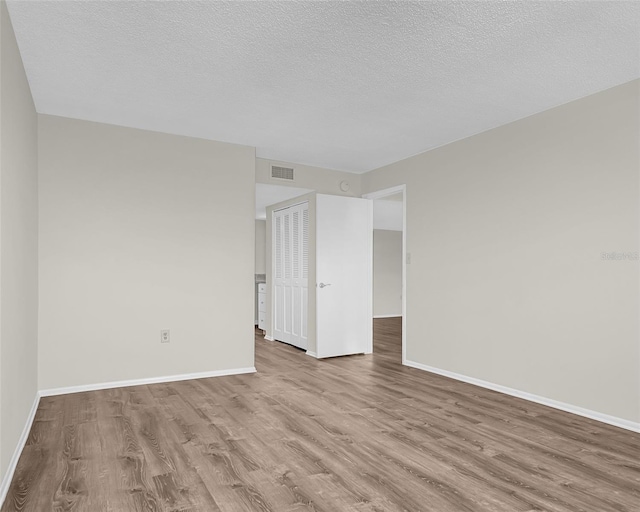 spare room featuring a textured ceiling and wood-type flooring