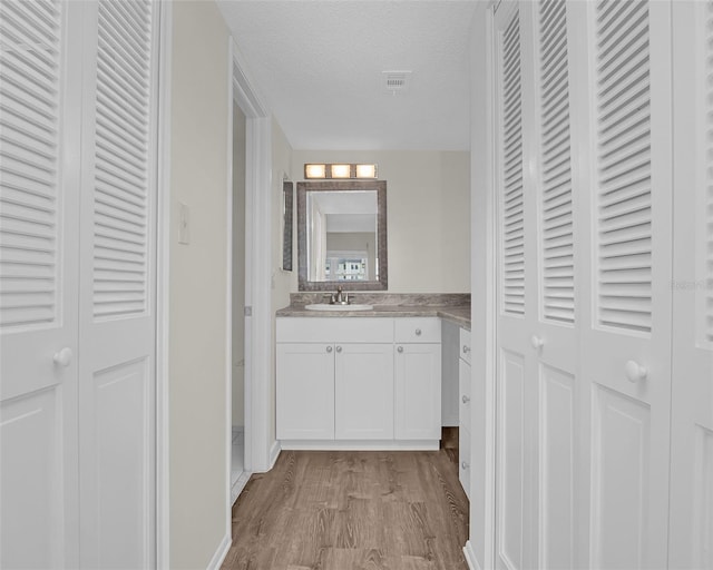 bathroom with a textured ceiling, hardwood / wood-style flooring, and vanity