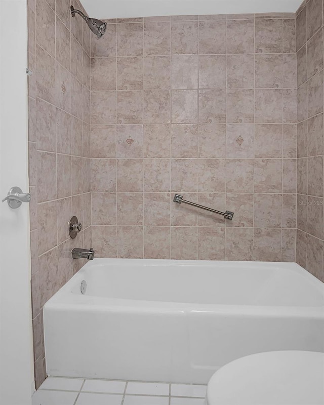 bathroom with tile patterned floors, toilet, and tiled shower / bath