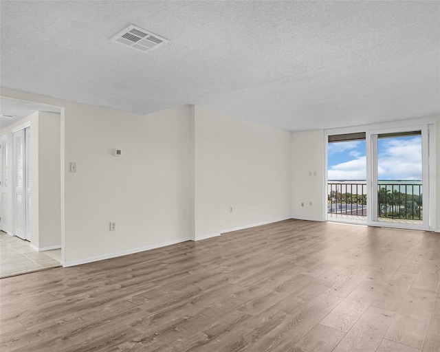 spare room featuring a textured ceiling and light hardwood / wood-style flooring