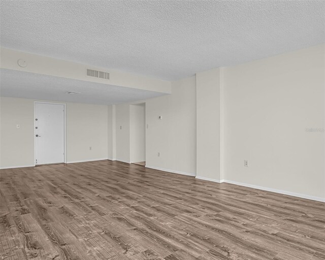 spare room with a textured ceiling and hardwood / wood-style floors