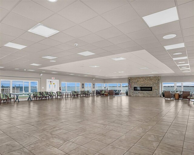 interior space featuring a fireplace, light tile patterned floors, and a drop ceiling