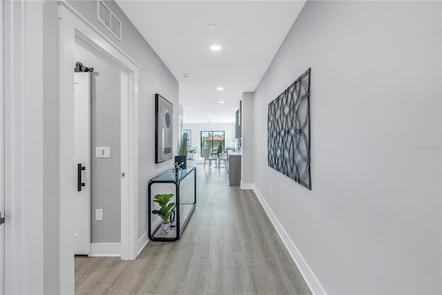 hall with light wood-style flooring, visible vents, baseboards, and recessed lighting