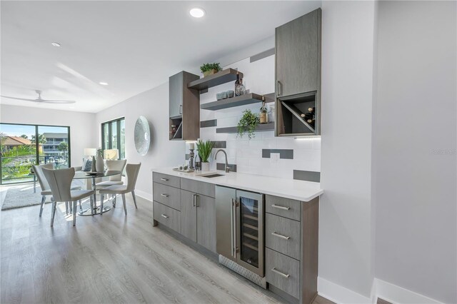 kitchen featuring wine cooler, light wood finished floors, open shelves, tasteful backsplash, and light countertops