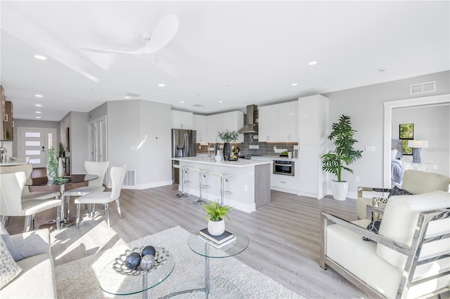 living room with ceiling fan, sink, and light hardwood / wood-style flooring