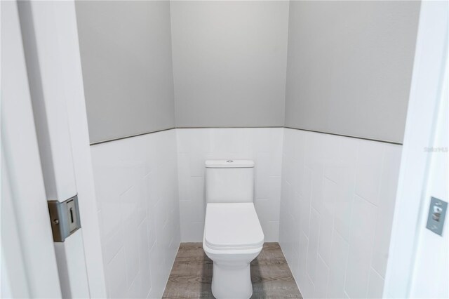 bathroom featuring wainscoting, toilet, and tile walls