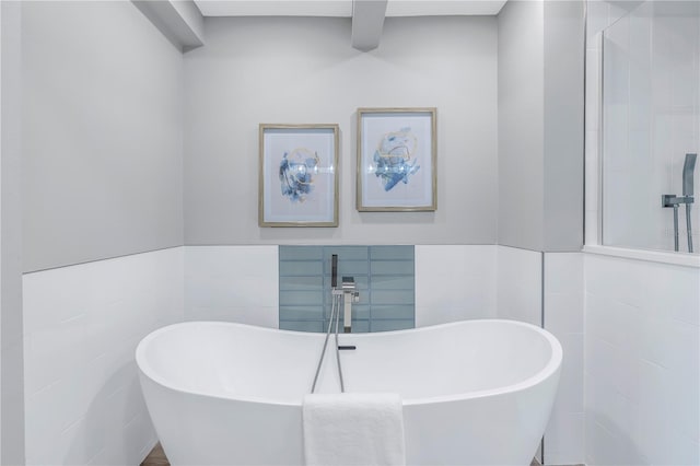 bathroom featuring wainscoting, a soaking tub, and tile walls