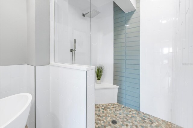 full bath with a walk in shower, a freestanding bath, and tile walls