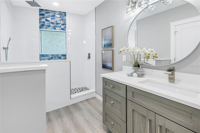 bathroom featuring wood finished floors, vanity, and a walk in shower