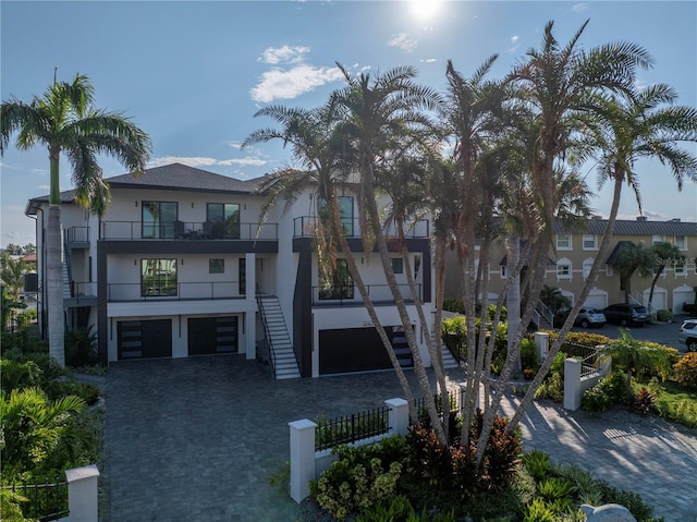 exterior space with stairs, decorative driveway, a fenced front yard, and a garage